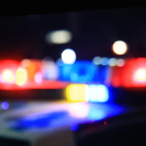 Blurred police car lights with red and blue sirens in the foreground, creating an abstract, bokeh effect