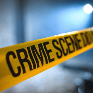 Yellow crime scene tape stretches across a dimly lit area, creating a mysterious atmosphere