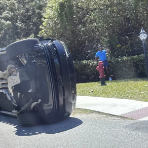 Golfer Tiger Woods stands by his overturned vehicle in Jupiter Island, Fla., on Friday, March 27, 2026. (AP Photo/Jason Oteri)